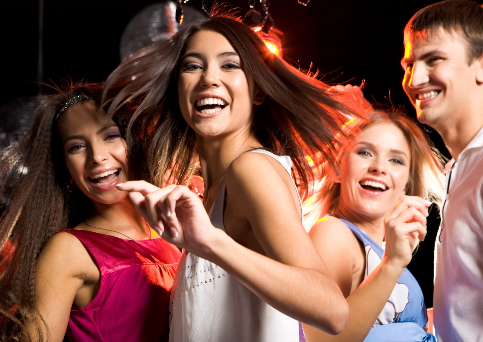 Portrait of laughing girl wearing white dress dancing among her friends